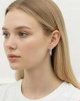 Modelo luciendo pendientes de aro Queens Candy de plata 925 chapada en platino con moissanitas brillantes de 2.5mm