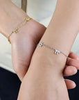 Pulsera Queens Candy plateada con dijes hamsa y zirconias brillantes en la muñeca de una mujer