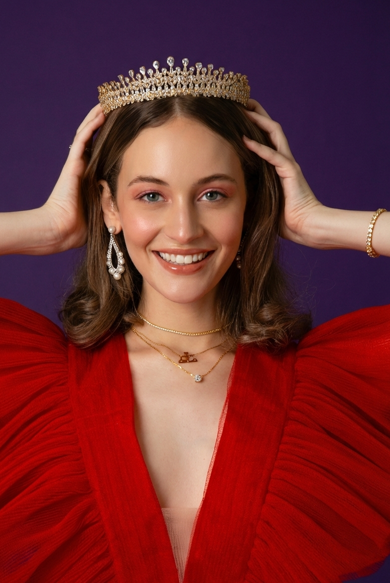 Woman wearing a tiara and red dress against a purple background