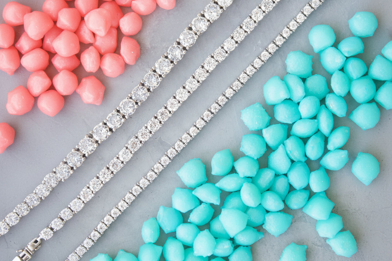 Close-up of red and blue candies with a silver tennis bracelets on a gray background
