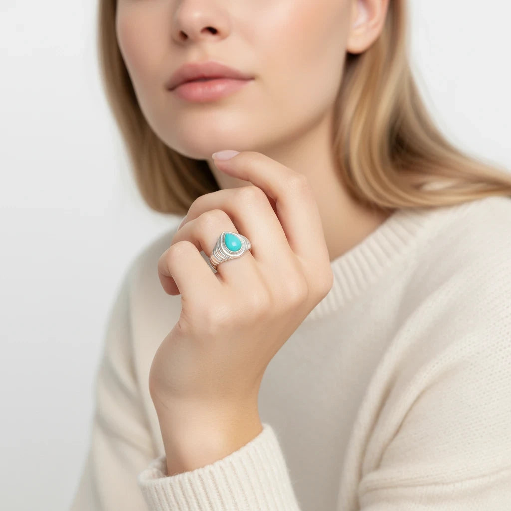 Queens Candy adjustable sterling silver ring featuring a teardrop turquoise stone and a ribbed band on a model's hand