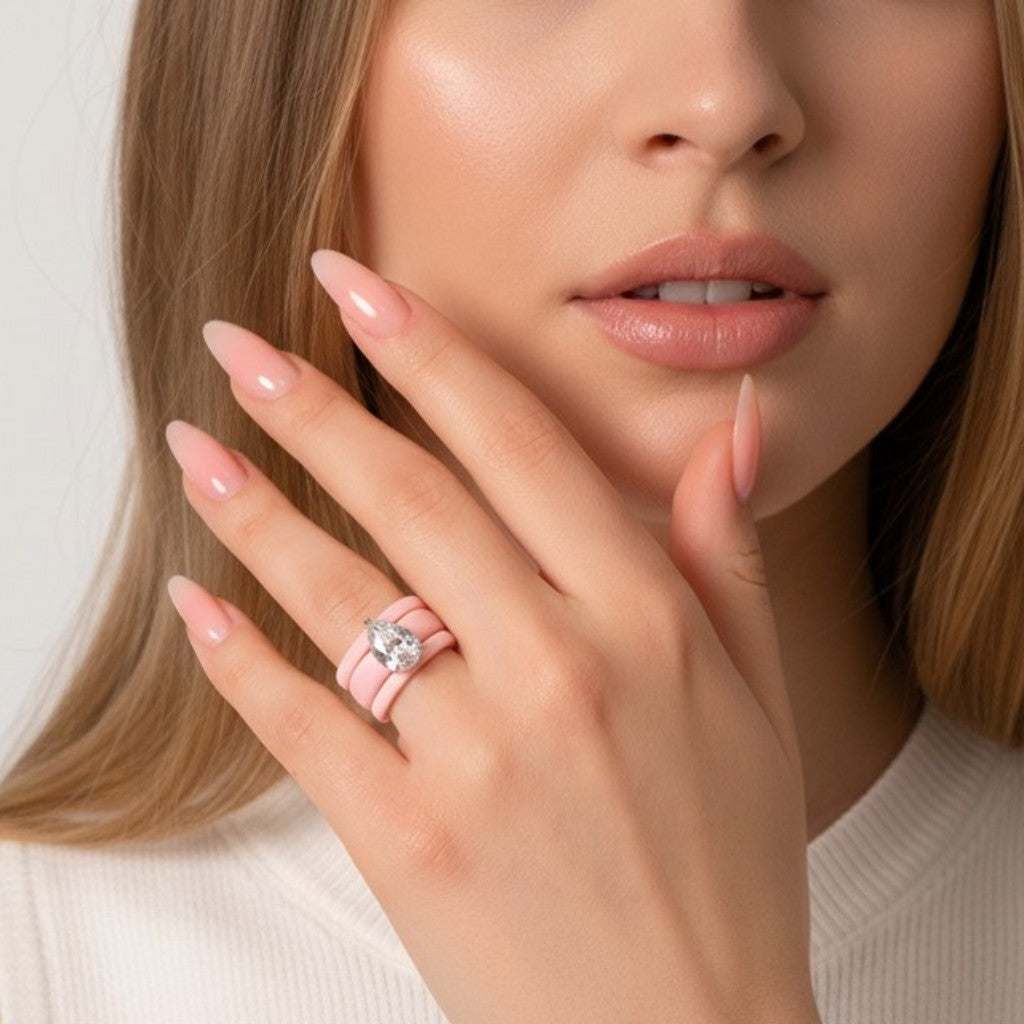 Anillo Queens Candy de silicona rosa pastel con tres aros apilados y una zirconia cúbica en corte pera en una mano
