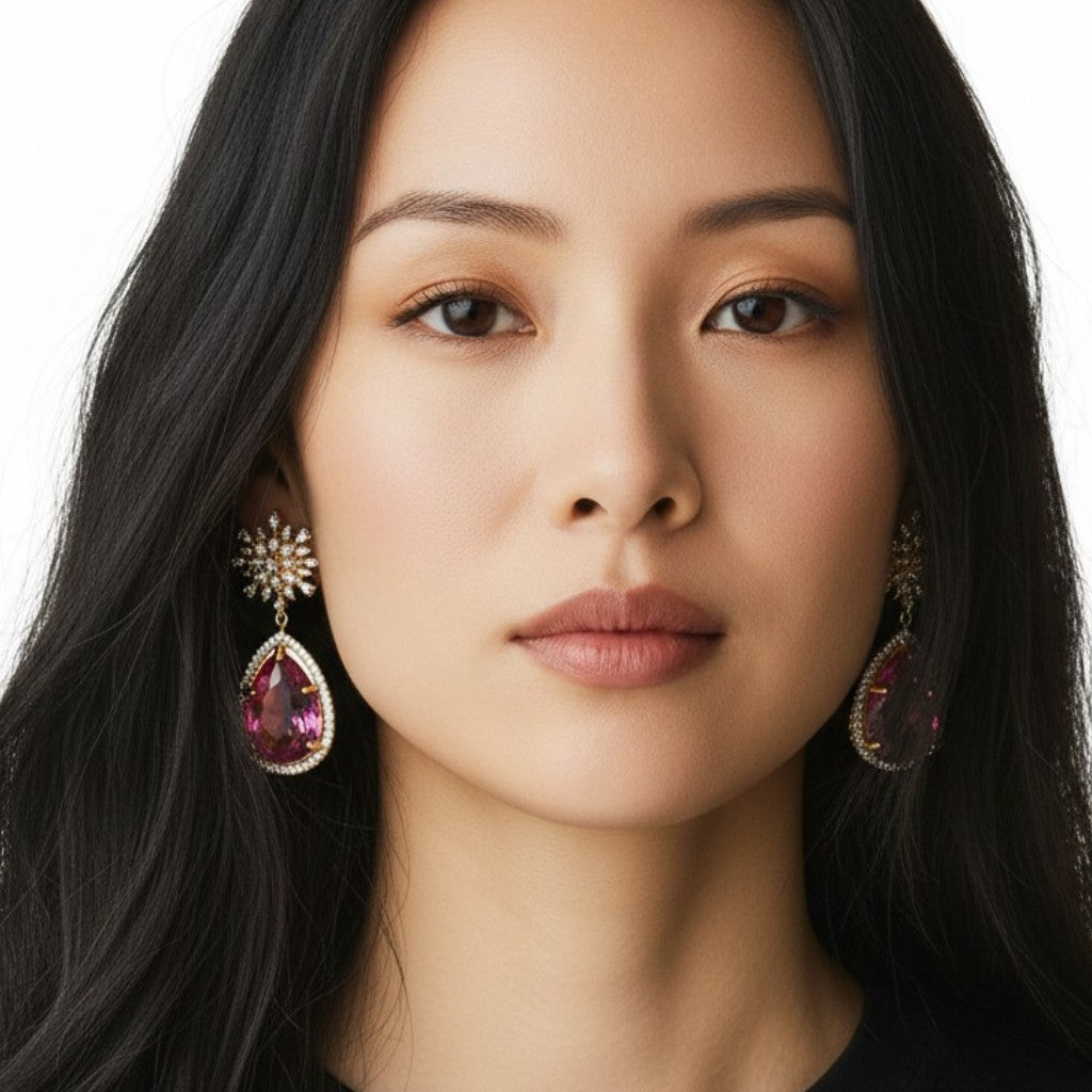 Aretes Bloom Drop de Queens Candy con diseño floral, zirconias y gota de cristal fucsia en baño dorado.