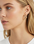 Aretes Queens Candy de doble aro en baño de oro con zirconias brillantes puestos en una modelo rubia