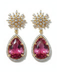 Aretes Queens Candy Bloom con top floral de zirconias y gota de cristal fucsia en cobre con baño dorado.