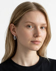 Modelo luciendo aretes hoop Queens Candy de 22mm en baño plateado con zirconias brillantes en todo el aro.
