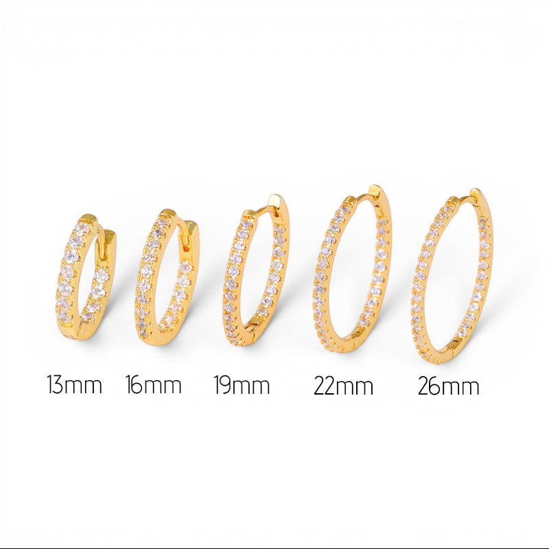 Aretes hoop Queens Candy dorados con zirconias en diferentes tamaños de 13mm a 26mm sobre fondo blanco