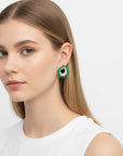 Modelo luciendo aretes Queens Candy Matcha Frost con zirconias cúbicas verdes y blancas en diseño geométrico vintage.