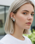 Ear cuff Queens Candy de cobre bañado en platino con circonitas verdes y blancas en una mujer rubia