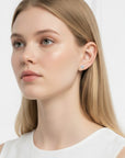Modelo luciendo pendientes de botón Queens Candy con moissanitas en forma de corazón, plata 925 y baño de platino.