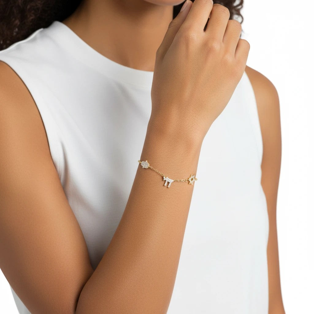 Pulsera Queens Candy de cobre con baño dorado, dijes de la suerte con zirconias cúbicas en la muñeca de una modelo.