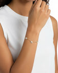Pulsera Queens Candy de cobre con baño dorado, dijes de la suerte con zirconias cúbicas en la muñeca de una modelo.