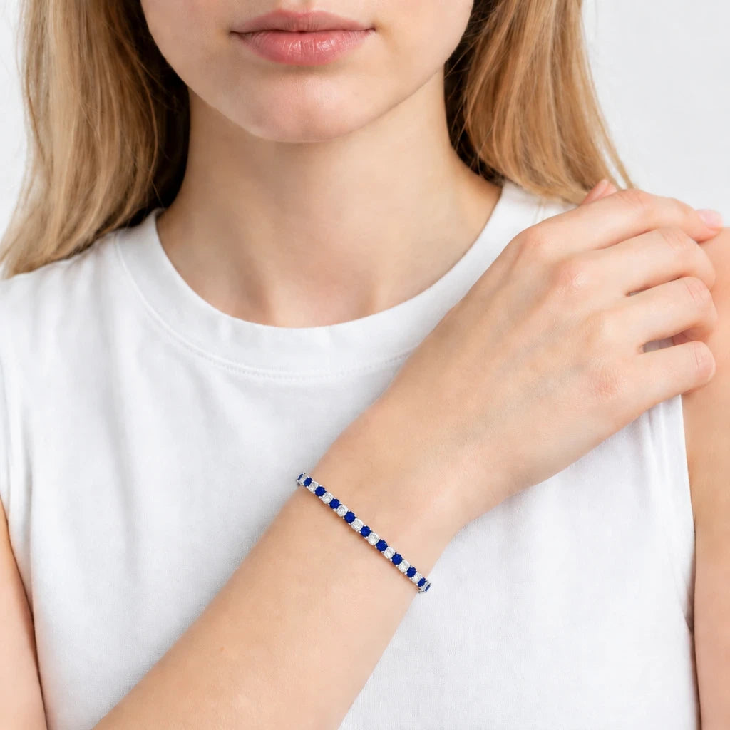 Pulsera de tenis Queens Candy con zirconias azules y blancas alternadas en baño plateado sobre muñeca de mujer