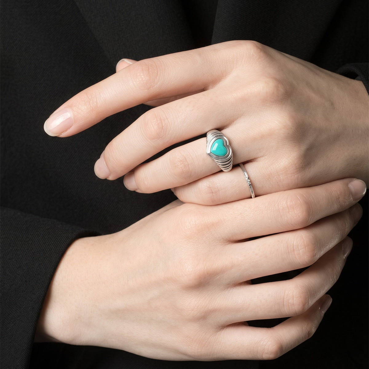 Queens Candy adjustable sterling silver heart ring with a turquoise stone and ribbed band on a woman's finger